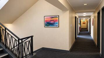 Un couloir d’hôtel avec un escalier, des revêtements de sol en moquette et un tableau encadré accroché au mur.