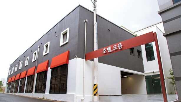 A building with a grey facade, red awnings, and a sign in a foreign language. - HOTEL MOMUM (Pohang)