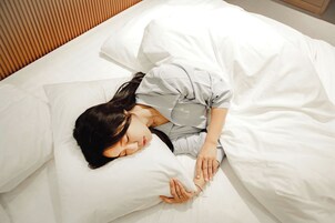 A person sleeping in a bed with white bedding.