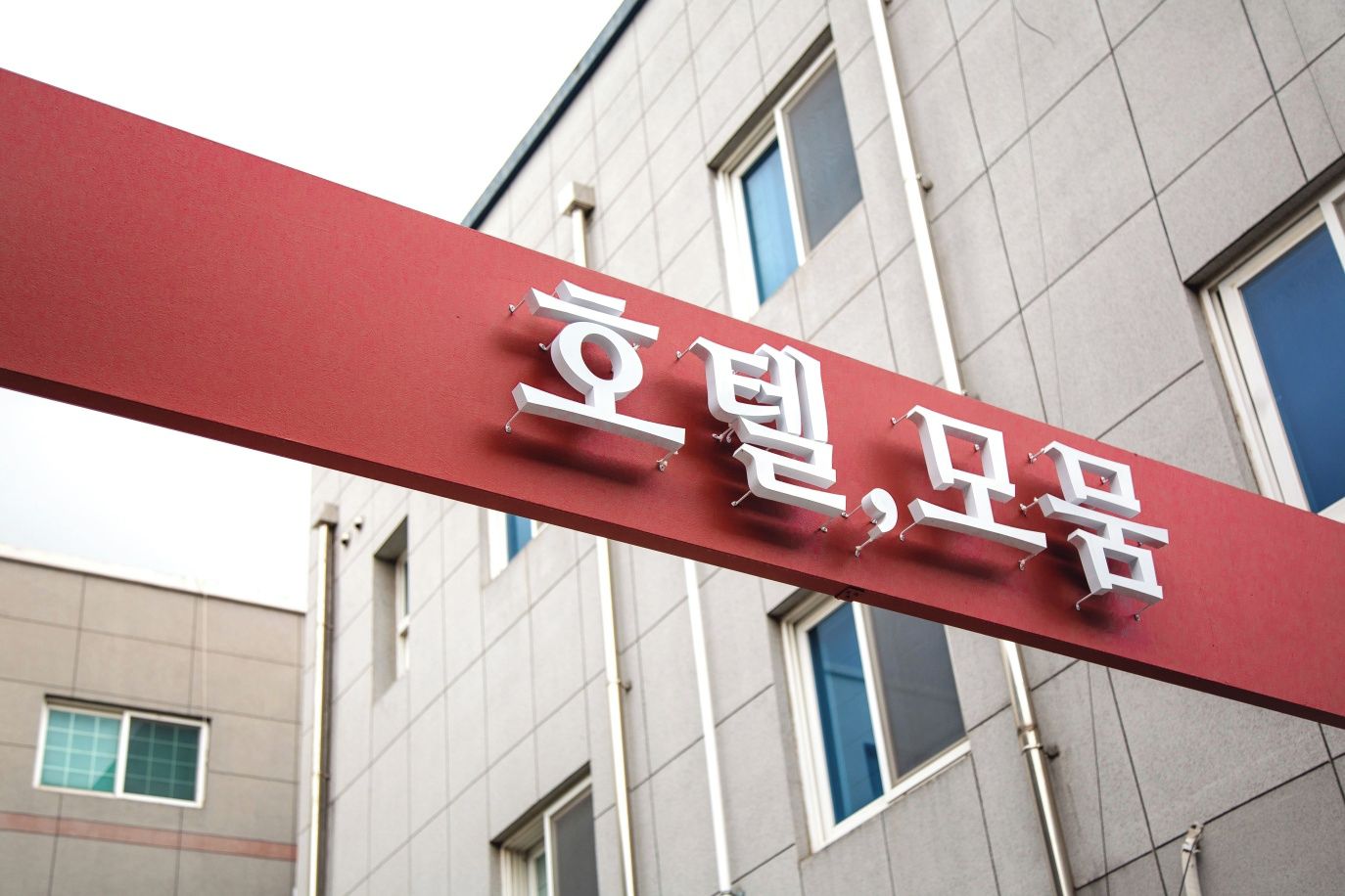 A red sign with white text, mounted on a building facade.