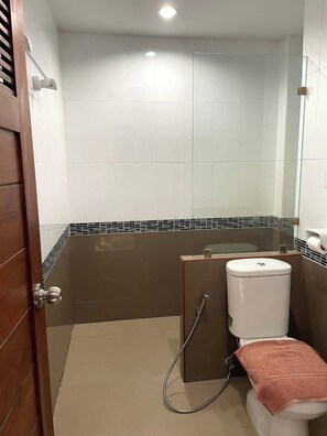 A bathroom with a shower, toilet, and a towel on the floor. - Al Ameen Hotel (Krabi)