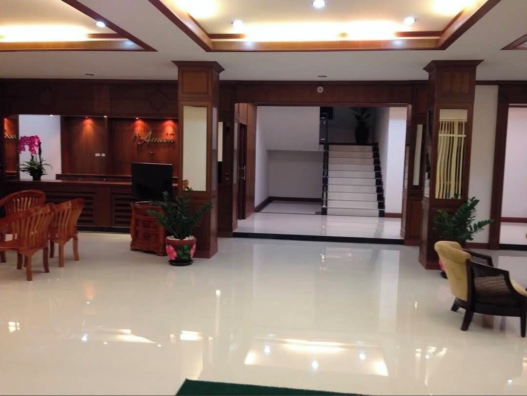 A reception area with a reception desk, chairs, potted plants, and a staircase leading to an upper floor.