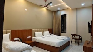 Habitación de hotel con dos camas, ventilador de techo, televisión y escritorio.
