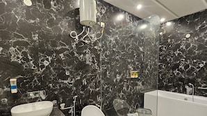 Un baño moderno con pared de mármol negro, lavamanos blanco, inodoro y bañera.