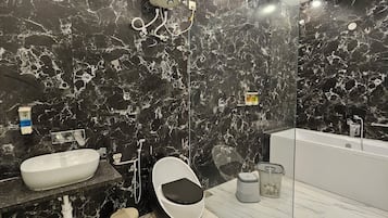 A modern bathroom with a black marble wall, a white sink, a toilet, and a bathtub.