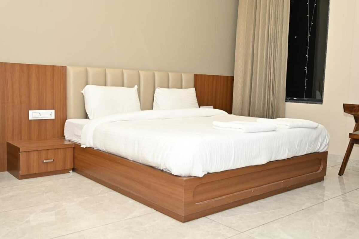 A modern bedroom with a wooden bed frame, white bedding, and a nightstand.