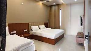 Habitación de hotel con dos camas, ventilador de techo, televisor de pantalla plana y minibar.