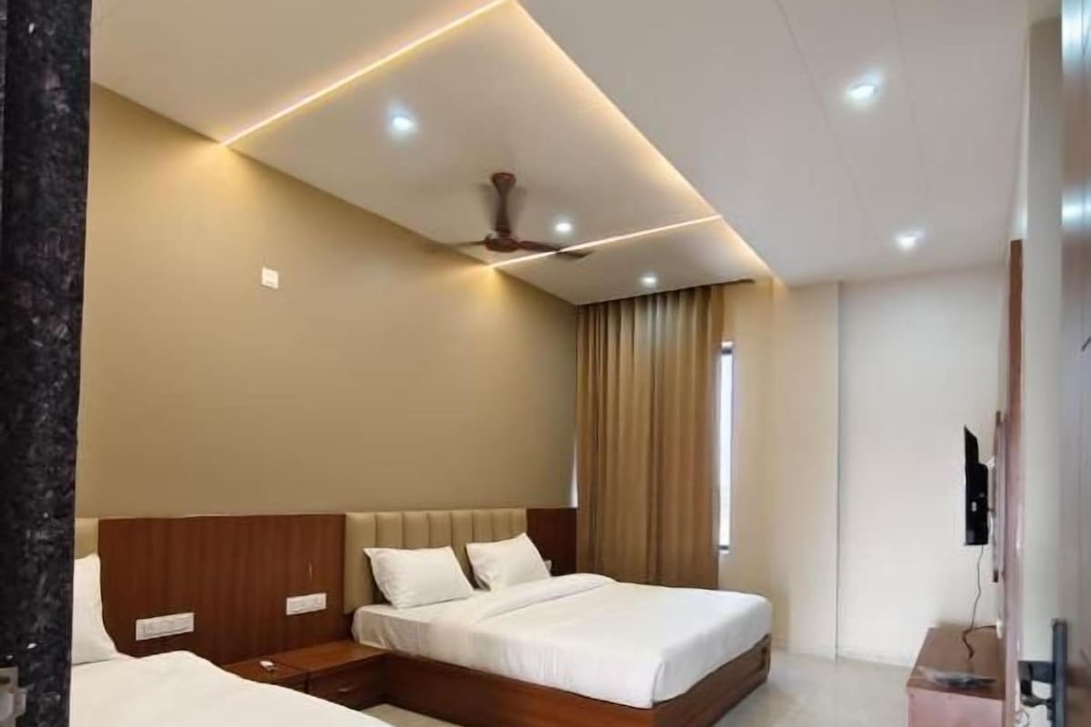A hotel room with two beds, a ceiling fan, a flat-screen TV, and a minibar.