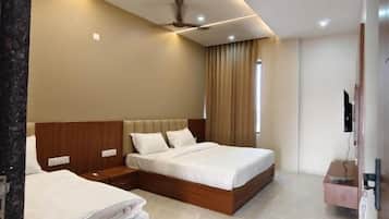 A hotel room with two beds, a ceiling fan, a flat-screen TV, and a minibar.