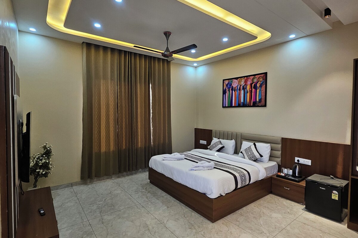 A modern bedroom with a bed, bedside tables, a ceiling fan, and a small refrigerator.