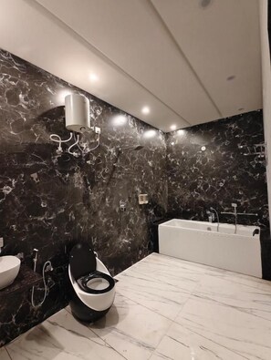 A modern bathroom with a marble wall, a toilet, a bidet, a bathtub, and a shower. - Sunrise Resorts (Jaisalmer)