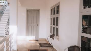 Un interior moderno con una escalera, una puerta y una zona de estar con sillas y una mesa.