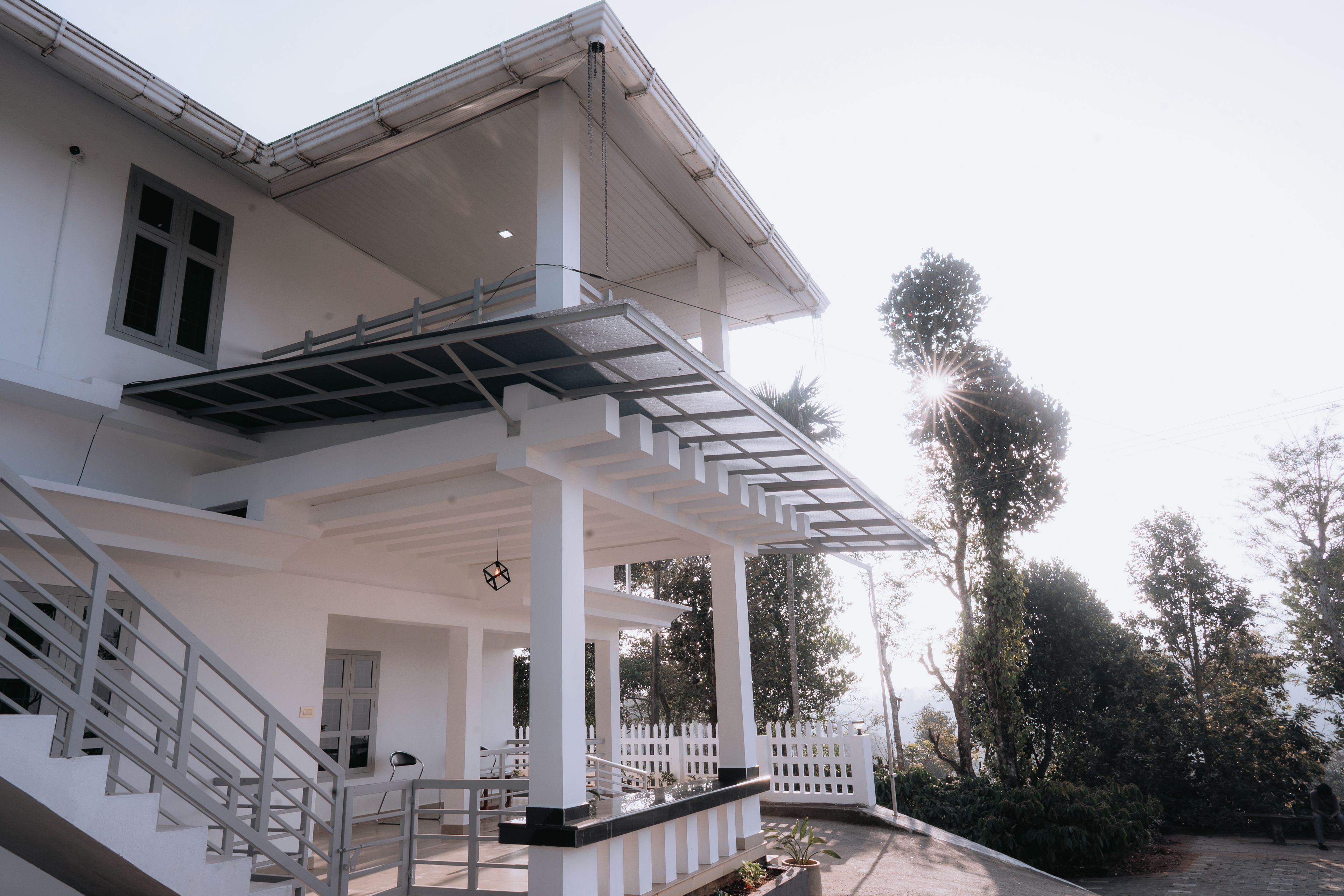 A building with a covered porch, a staircase, and a view of trees.