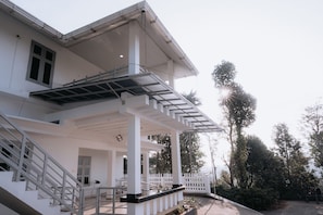 Un edificio con un porche cubierto, una escalera y vistas a árboles.