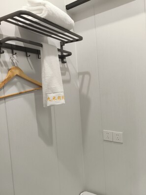 A bathroom with a towel rack, a wooden hanger, and a wall socket. - Jiumihutong Homestay (Qingdao)