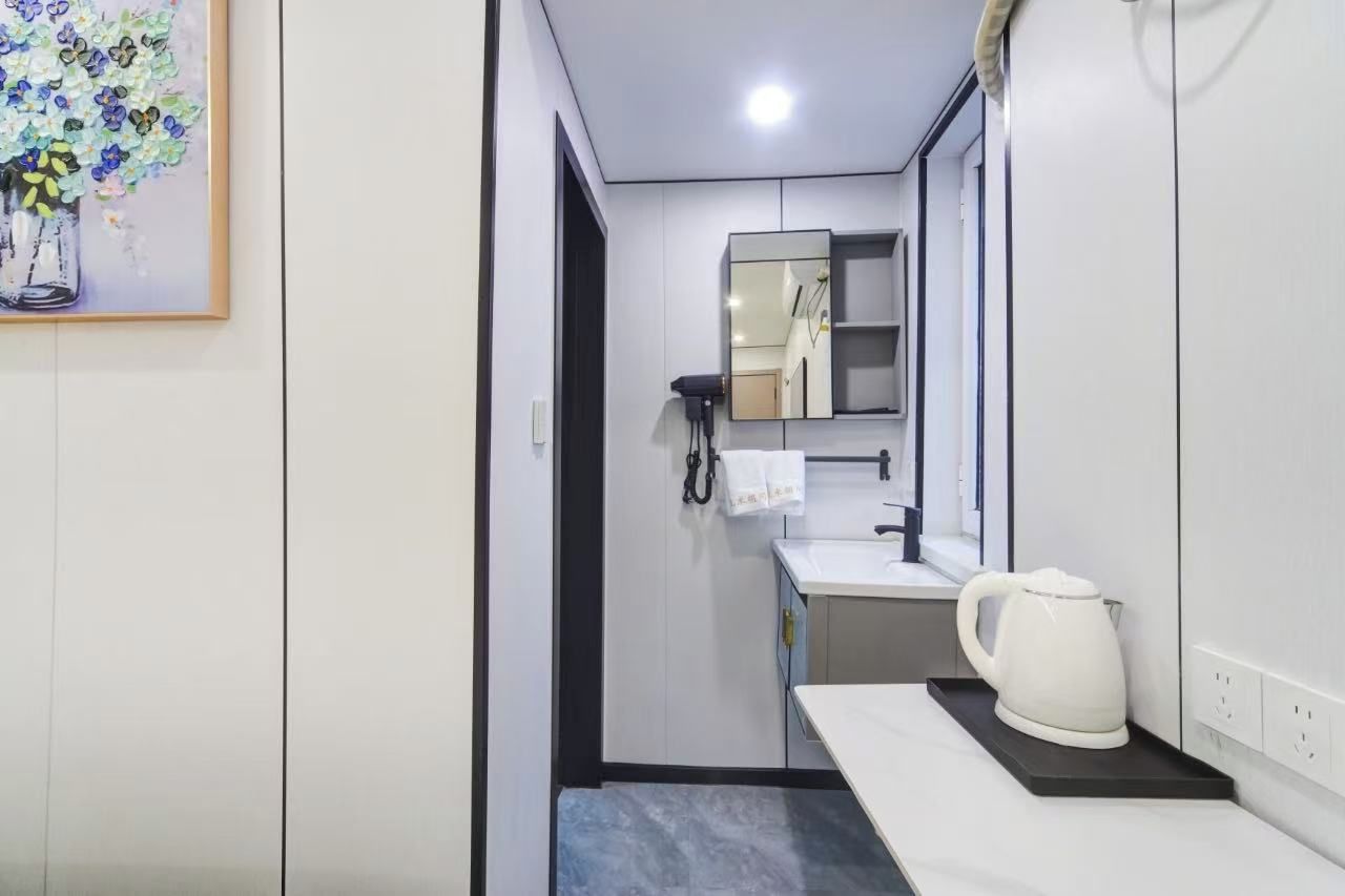 Casa de banho moderna com lavatório branco, espelho, porta-toalhas e chaleira branca sobre um tabuleiro.