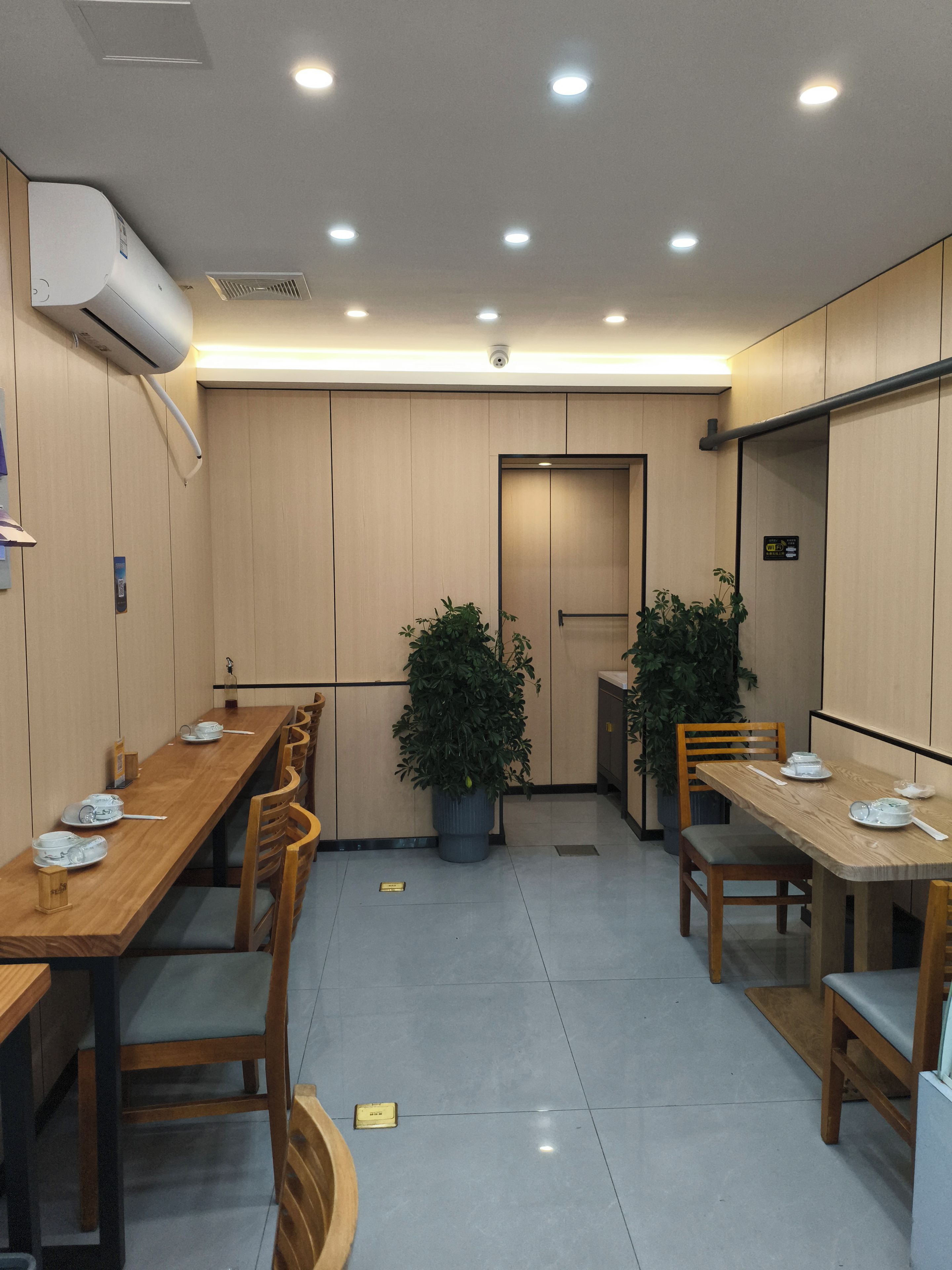 Uma sala de conferências com mesas compridas, cadeiras e plantas em vasos.