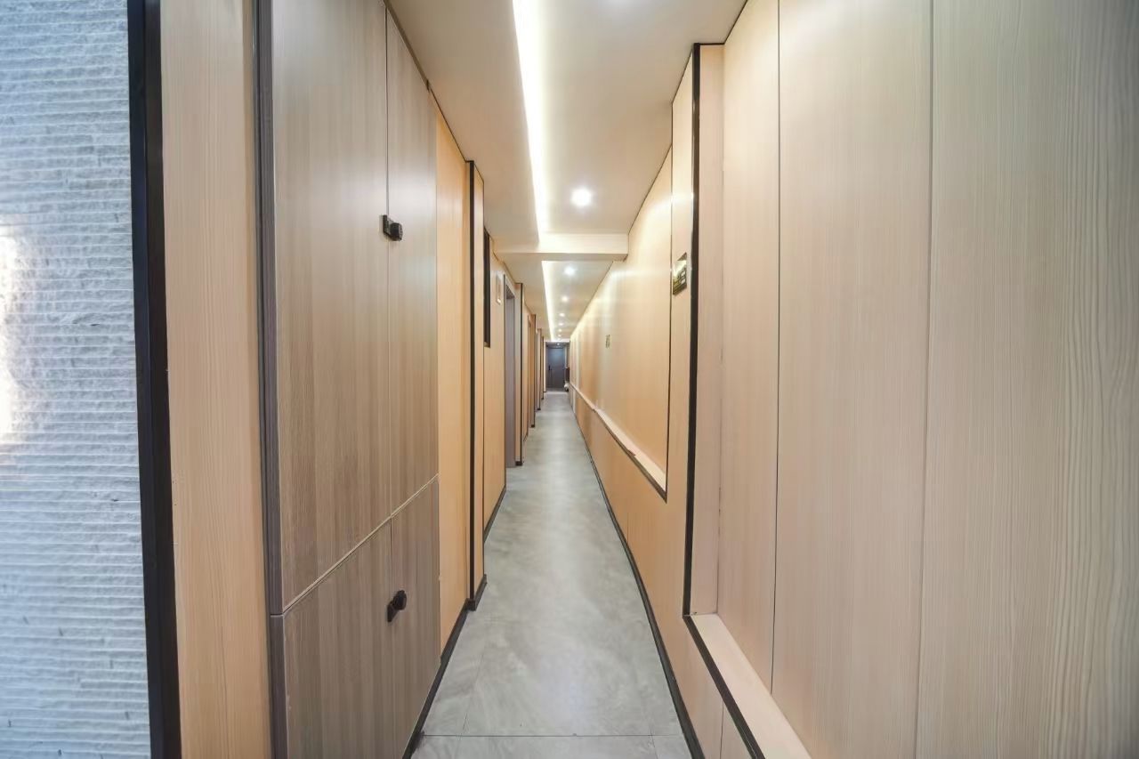 Un pasillo largo y estrecho con paneles de madera en las paredes y piso de baldosas.