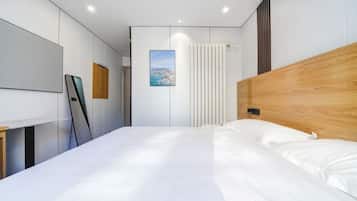Un dormitorio moderno con una cama grande, cabecera de madera, pared blanca con una imagen de un paisaje urbano y una cortina blanca.