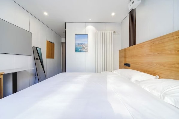 Un dormitorio moderno con una cama grande, cabecera de madera, pared blanca con una imagen de un paisaje urbano y una cortina blanca.