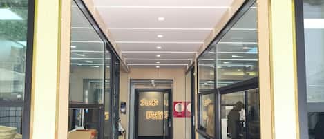 A corridor with a tiled floor leading to a door with a sign.