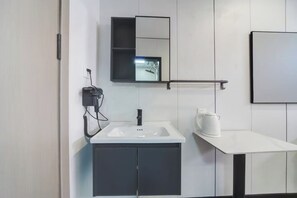 A modern bathroom with a white sink, black cabinets, a mirror, and a white countertop. - Jiumihutong Homestay (Qingdao)