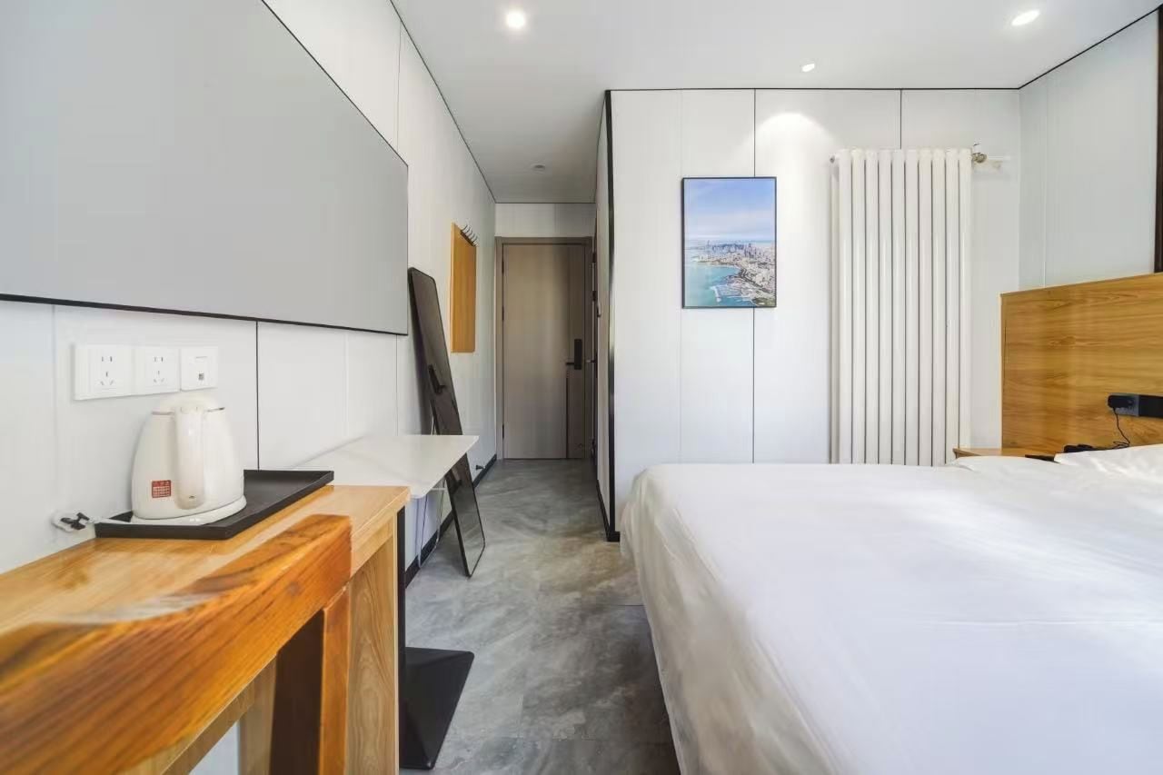 Habitación de hotel moderna con una cama, un escritorio con hervidor, vista a un paisaje urbano y un radiador.