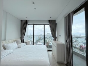 A modern hotel room with a large bed, a seating area, and a city view. - 
Experience luxury by the sea in this elegant Da Nang (Đà Nẵng)