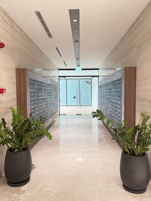 A hallway with a mirrored wall, a glass door entrance, and potted plants. - 
Experience luxury by the sea in this elegant Da Nang (Đà Nẵng)