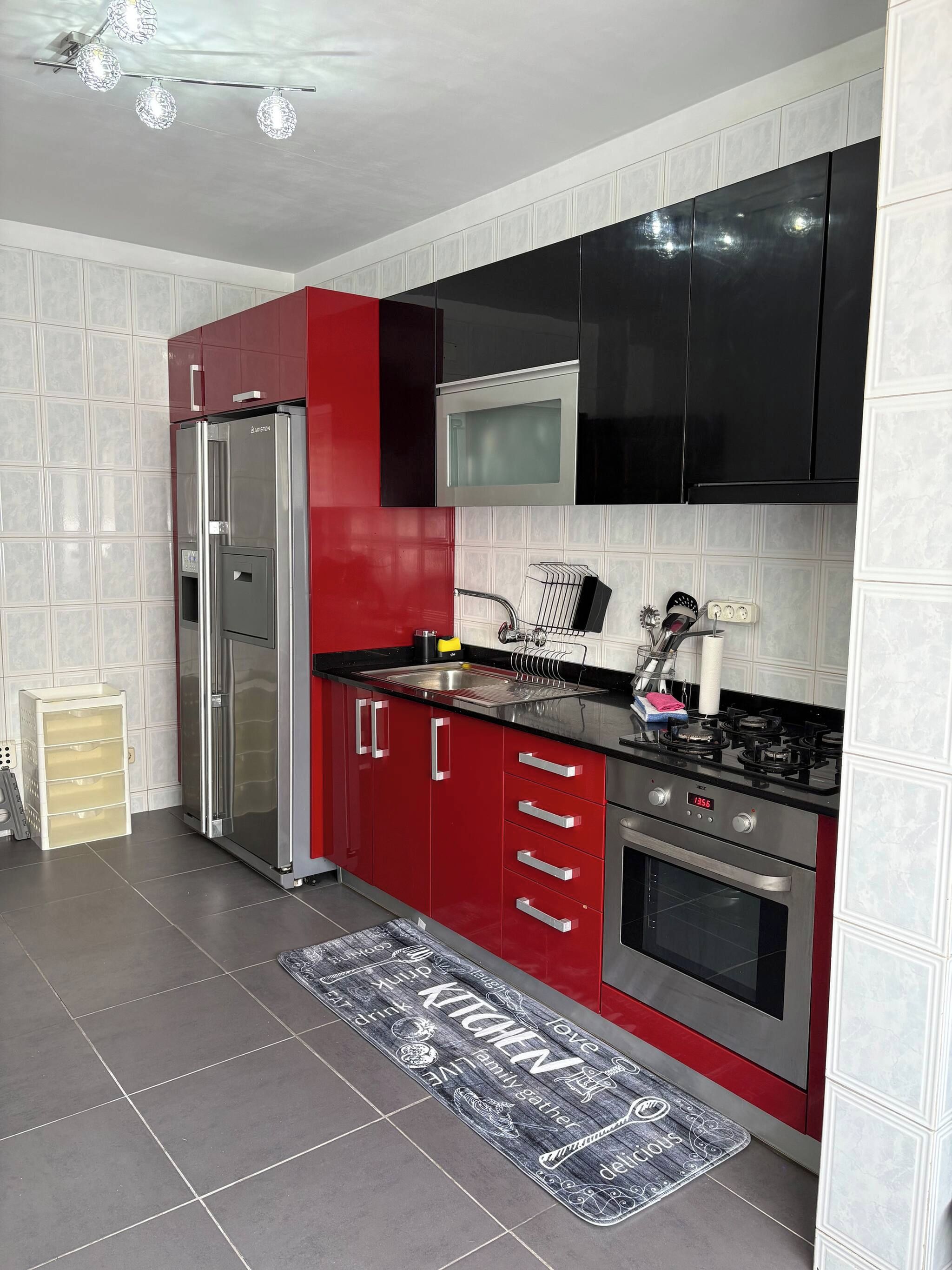 Une cuisine moderne équipée d’un réfrigérateur, d’un four à micro-ondes, d’une cuisinière et de meubles de rangement rouges.