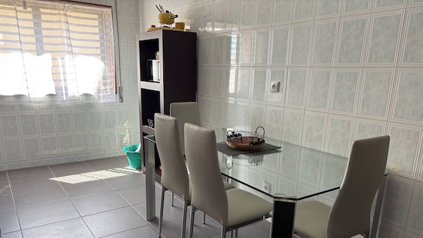 Une cuisine moderne avec une table à manger en verre, quatre chaises et un meuble noir.