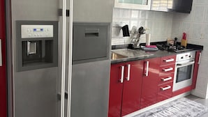 Une cuisine équipée d’appareils électroménagers en acier inoxydable, de placards rouges, d’un four à micro-ondes et d’un four encastré.