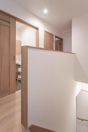A room with a wooden floor, a white partition, and a door leading to another room. - NIKYO Hoshi House Private Villa OSAKA (Osaka)