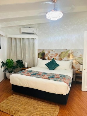 A bedroom with a bed, a ceiling fan, an air conditioning unit, a window with curtains, and a potted plant. - Residence No. 5 (Martintar, Nadi)