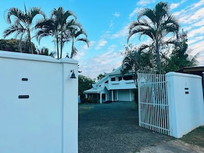 A gated entrance to a property with a white gate and a white building in the background.