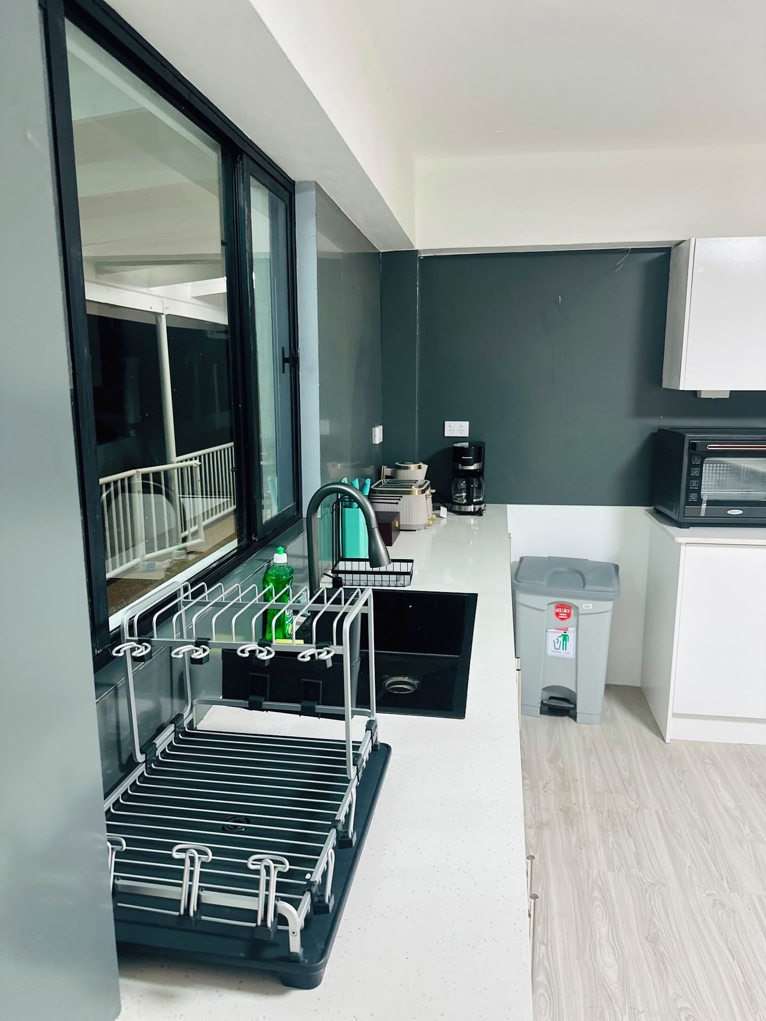 A compact kitchenette with a built-in microwave, a coffee maker, and a trash bin.