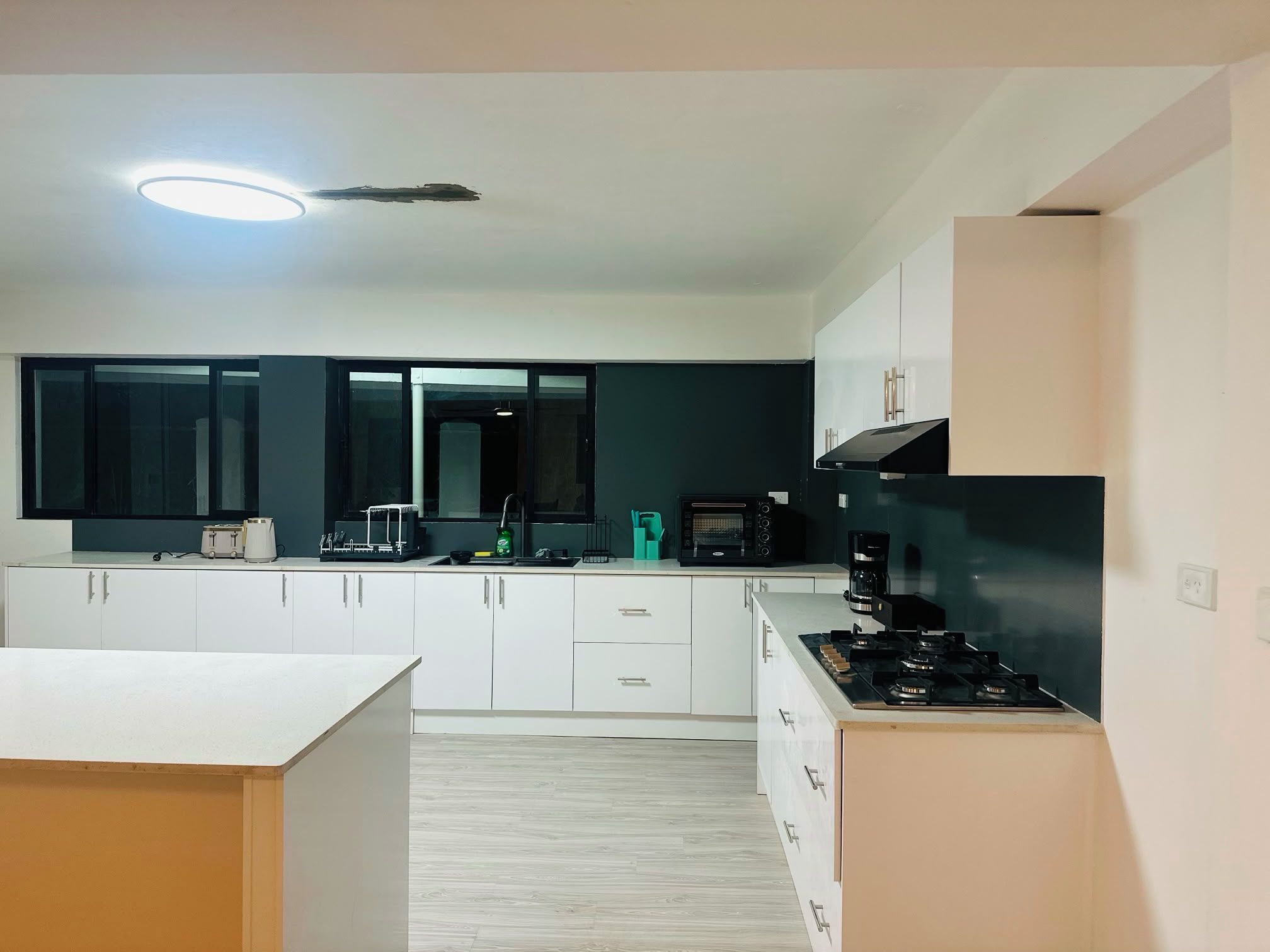 A modern kitchen with white cabinets, a black stove, and a built-in oven.