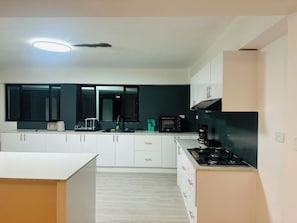 A modern kitchen with white cabinets, a black stove, and a built-in oven.