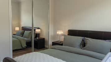 Une chambre à coucher avec un lit, deux tables de chevet, un miroir et une petite table.