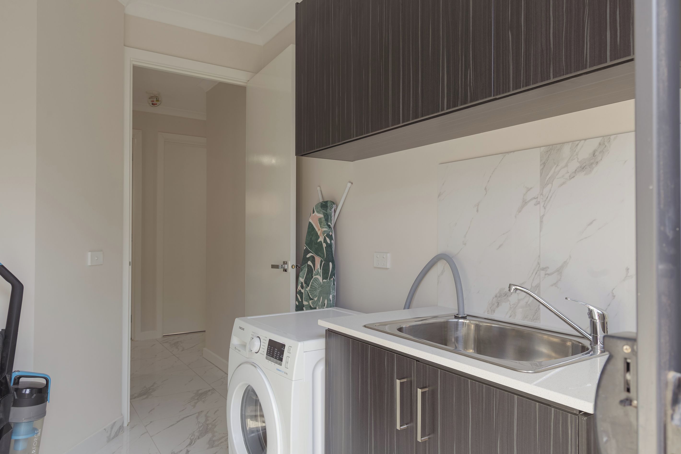 A compact kitchen with a built-in washing machine, a sink, and a door leading to another room.