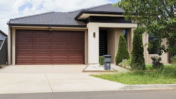 Une maison d'habitation avec un grand portail de garage, une boîte aux lettres et une pelouse bien entretenue.
