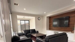 Una sala moderna con un sofá modular, una mesa de centro y un televisor de pantalla plana montado en la pared.