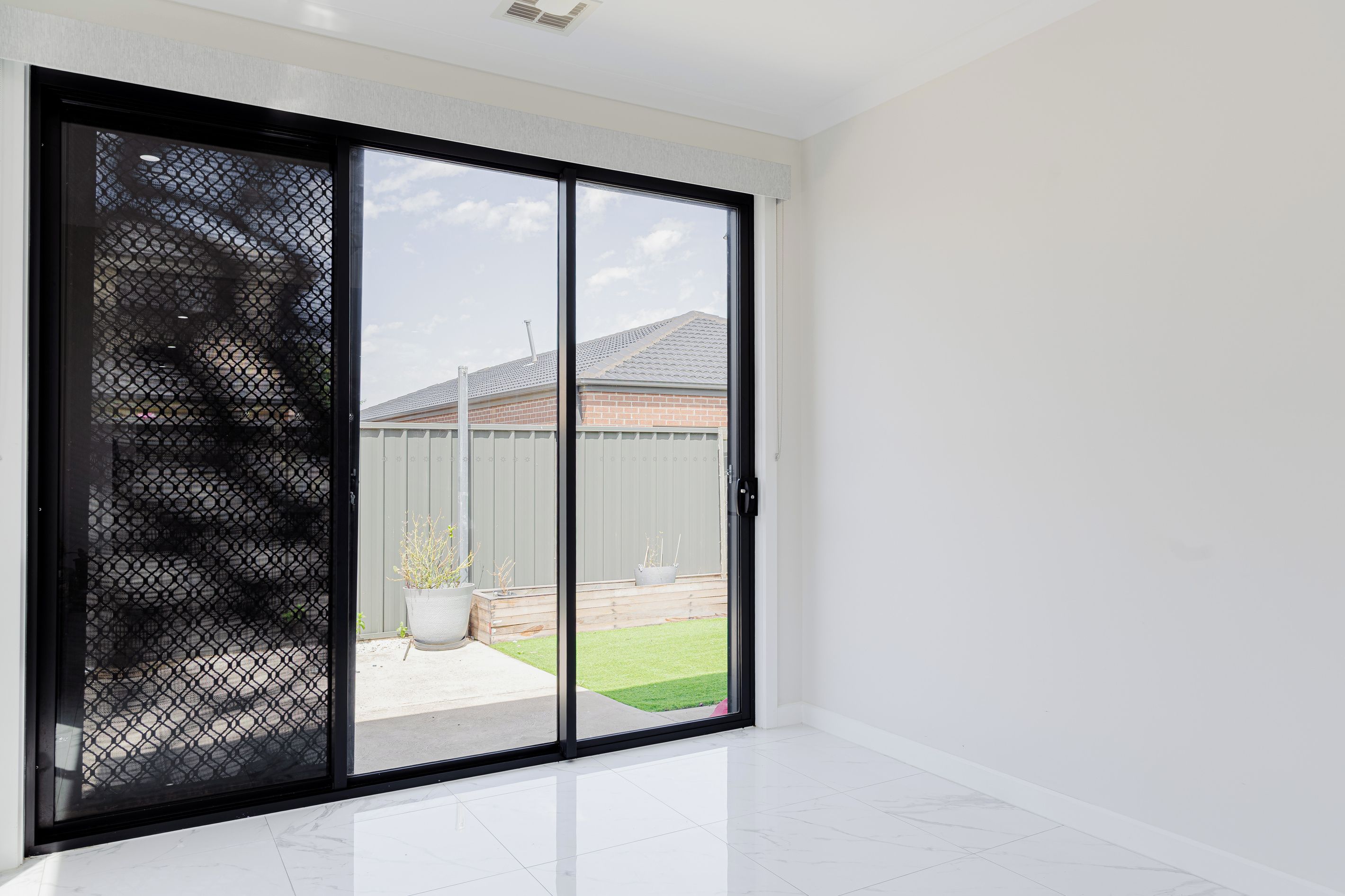 A room with a sliding glass door leading to a backyard with a lawn and a fence.