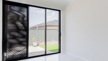 A room with a sliding glass door leading to a backyard with a lawn and a fence.