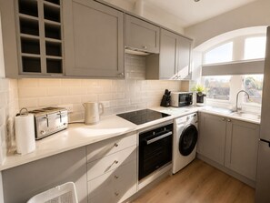 A modern kitchen with a built-in oven, microwave, and a washing machine. - Comfortable Apartment with free parking sleeps 4 and is close to Longleat. (Westbury)