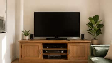 Un salon avec un meuble de rangement en bois pour les appareils multimédias, un téléviseur à écran plat et un canapé vert.