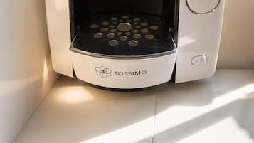 Une machine à café Tassimo au design noir et blanc, posée sur un rebord de fenêtre.