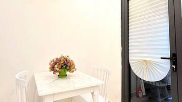 Un comedor con una mesa y sillas blancas, una lámpara colgante y una puerta con persiana.