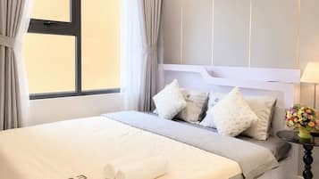 Un dormitorio moderno con una cama grande, una mesita de noche con lámpara y una ventana con cortinas.