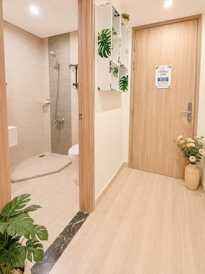 Casa de banho de hotel com chuveiro, sanita e porta de madeira com um aviso.